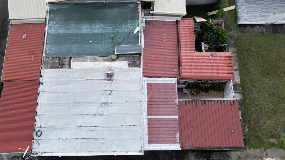 Chantier de toiture réalisé par Mes Primes Rénovations à Fort-de-France : couvertures mixtes tôle et bac acier sur un quartier dense